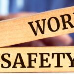 A man sitting at a table stacking an oblong wooden block reading "Work" on top of a block reading "Safety."