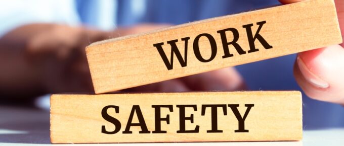 A man sitting at a table stacking an oblong wooden block reading "Work" on top of a block reading "Safety."