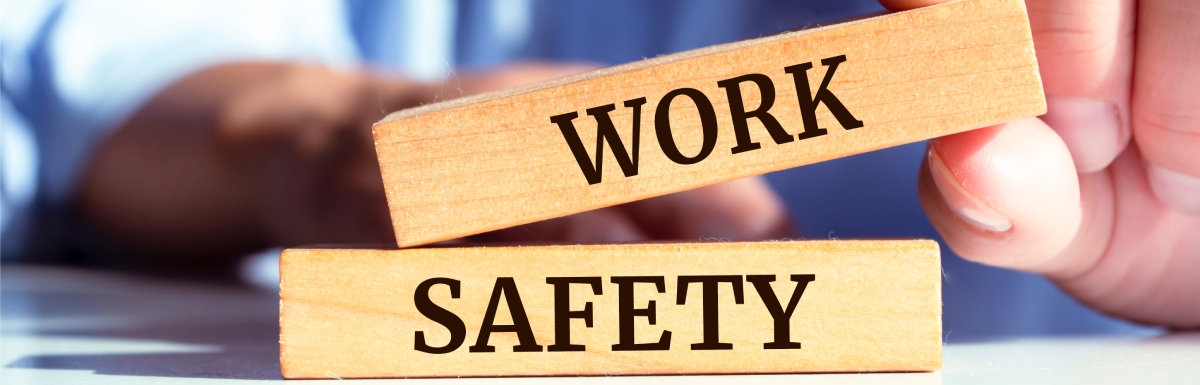 A man sitting at a table stacking an oblong wooden block reading "Work" on top of a block reading "Safety."