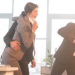 Three workers run in an office building during an emergency. The one leading the group holds a fire extinguisher.