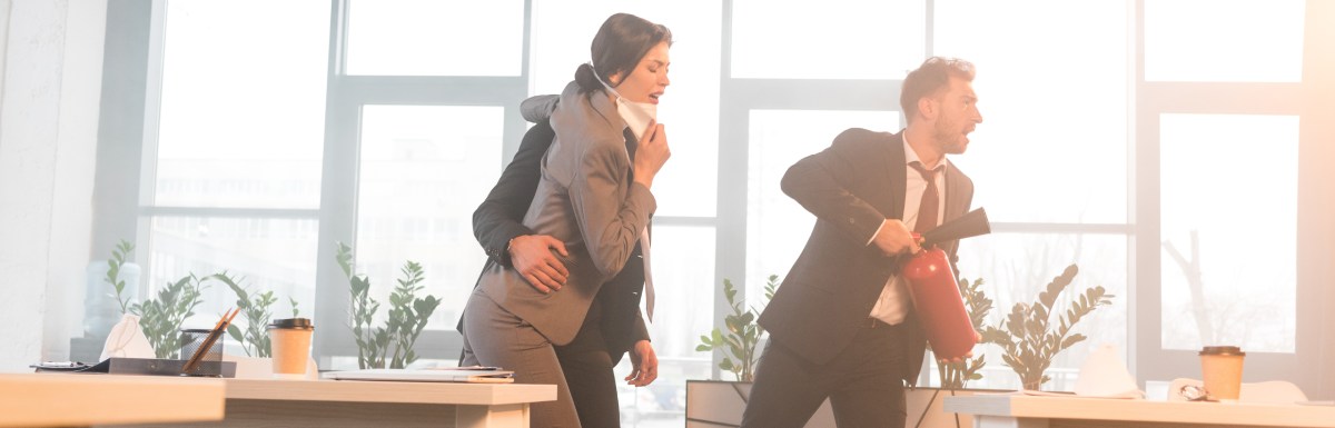 Three workers run in an office building during an emergency. The one leading the group holds a fire extinguisher.