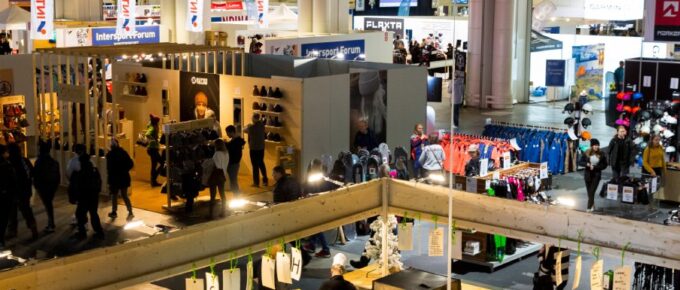 An aerial view of a large trade show. Attendees walk between different booth areas.