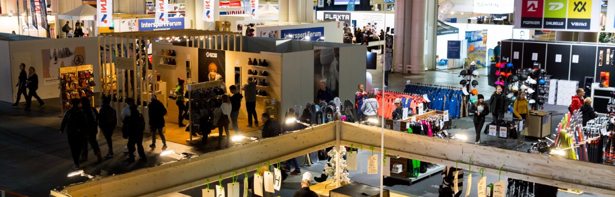 An aerial view of a large trade show. Attendees walk between different booth areas.
