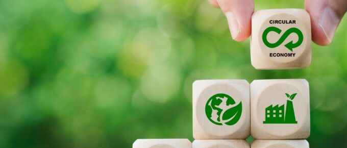A person stacking wooden blocks that have green icons representing recycling and other sustainability ideas.
