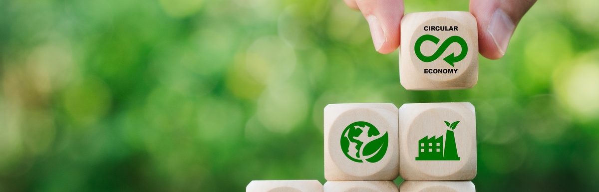 A person stacking wooden blocks that have green icons representing recycling and other sustainability ideas.