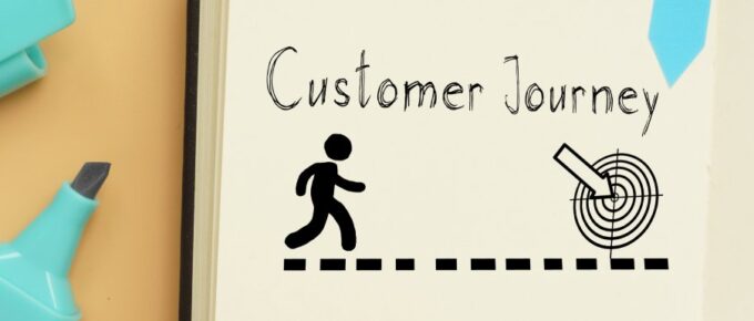 The brainstorming of a customer journey map on a notebook pad. There is a pen on the notebook and a paper clip nearby.