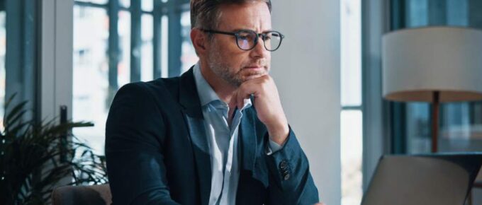 A businessman uses a laptop for online reading, with a facial expression that indicates he's engaged in problem-solving.