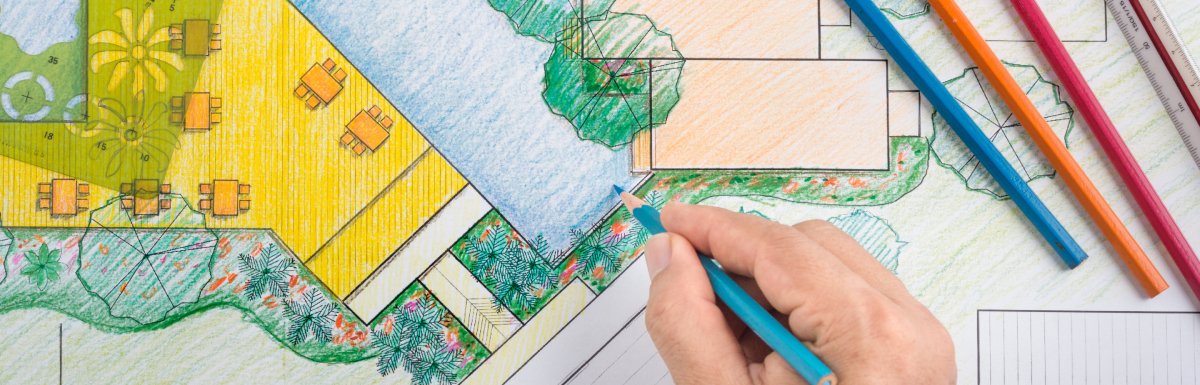 Colored landscape design plan showing pool, trees, patio areas, and drawing tools with pencils, rulers, and templates.