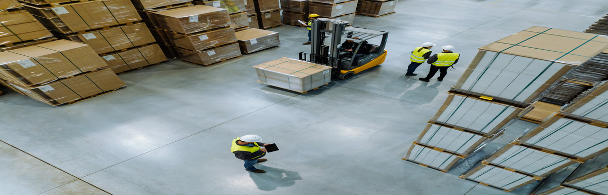 An overhead view of a warehouse storage space. There are multiple workers on the floor and a forklift.