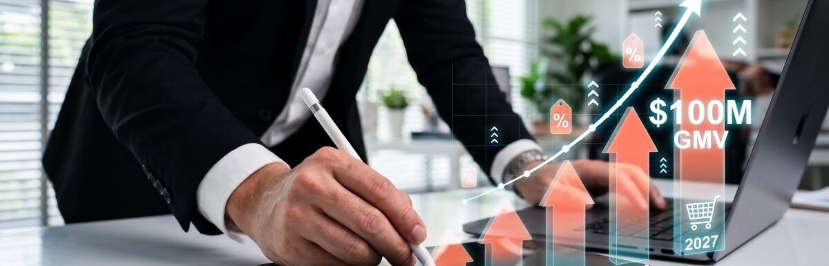 A person in a suit using a stylus on a tablet beside digital sales arrows, a laptop, and 100M GMV text.