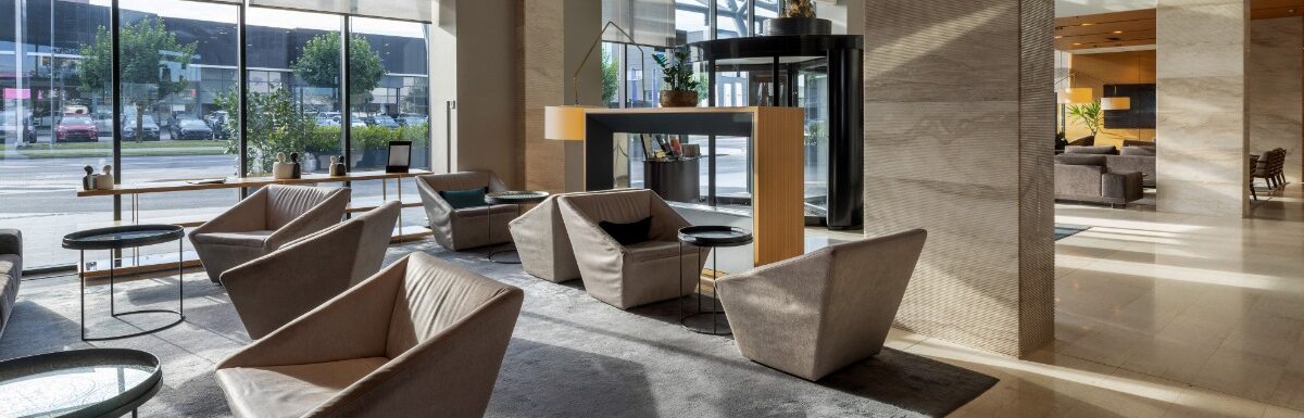 A large commercial entrance area to an office building. There are modern chairs and pillars around the space.